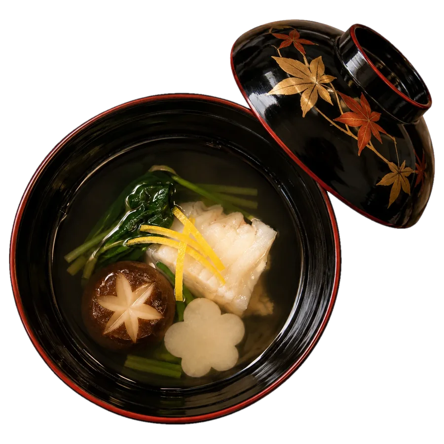 Clear dashi soup in a black lacquer bowl with sea bream, a shiitake cut into a star, a plum-blossom turnip and yuzu peel; the maple-leaf lid rests beside it